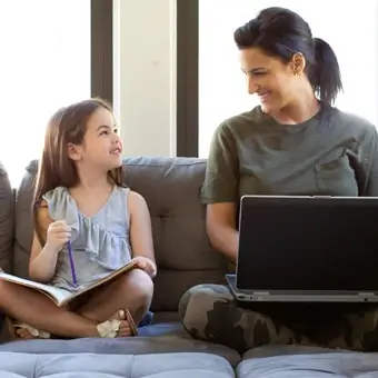 Active duty mom sitting next to her daughter while on a laptop