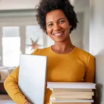 Military spouse leaning against the wall with a stack of books